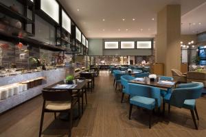 黄岛青岛东方影都希尔顿逸林酒店的餐厅设有桌子、蓝色椅子和柜台