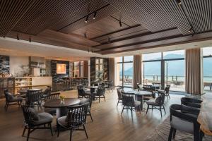 印渚杭州桐庐康莱德酒店的餐厅设有桌椅和窗户。