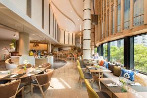 北京北京希尔顿酒店的餐厅设有木桌、椅子和窗户。