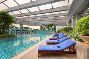 重庆重庆希尔顿酒店的大楼内一个带蓝色躺椅的游泳池