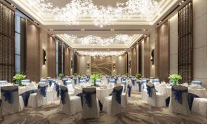菏泽菏泽希尔顿花园酒店				的宴会厅配有白色的桌椅和吊灯