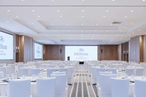 丽江丽江晶玺希尔顿酒店 的一间会议室,配有白色椅子和投影屏幕