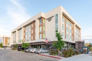 森尼维耳市Homewood Suites By Hilton Sunnyvale-Silicon Valley, Ca的停车场内有车辆停放的办公楼