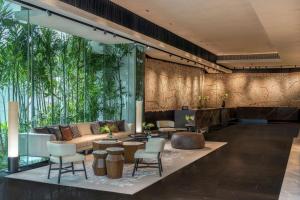 曼谷曼谷奔集路希尔顿逸林酒店的大堂配有沙发、椅子和树木