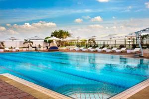 科伦坡科伦坡希尔顿酒店式公寓的一座大楼内的游泳池,配有椅子和遮阳伞