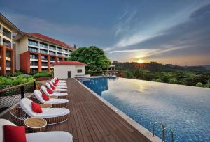 帕纳吉DoubleTree by Hilton Goa - Panaji的一个带躺椅和日落的度假游泳池