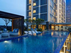 雅加达Hilton Garden Inn Jakarta Taman Palem的一座带躺椅的游泳池和一座建筑