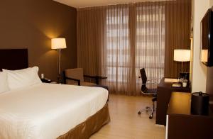 巴拿马城Holiday Inn Panama Distrito Financiero, an IHG Hotel的酒店客房,配有一张床、一张桌子和椅子