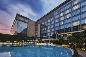 马尼拉Hilton Manila的大楼前设有大型游泳池的酒店