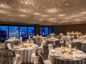 大阪大阪希尔顿酒店的宴会厅配有白色的桌椅和窗户。