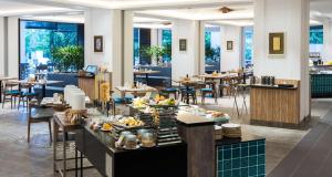 峇都丁宜槟城度假希尔顿逸林酒店的餐厅设有桌椅,展示食物