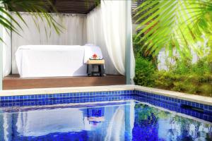 丹娜努斐济海滩希尔顿度假酒店的一个带白色浴缸和桌子的游泳池