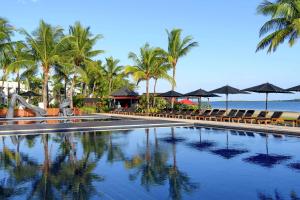 丹娜努斐济海滩希尔顿度假酒店的海滩上带椅子和遮阳伞的游泳池