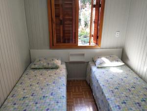 格拉玛多Gramado Família的两张床位于带窗户的房间内