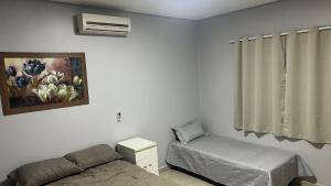 巴西利亚Linda casa em condomínio fechado的一间卧室配有一张床、一把椅子和一幅画