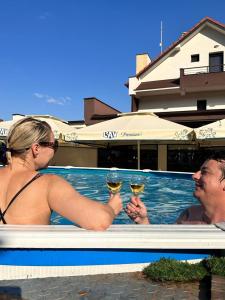 斯梅代雷沃Luxury Apartments 88的两人在游泳池内,享用一杯葡萄酒