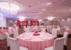 成田东京成田机场希尔顿酒店的宴会厅配有粉红色的桌椅和吊灯