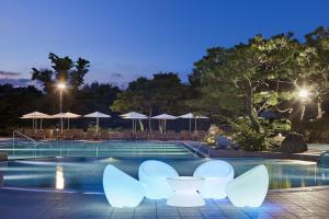 庆州庆州希尔顿酒店的夜间带白色椅子和遮阳伞的游泳池
