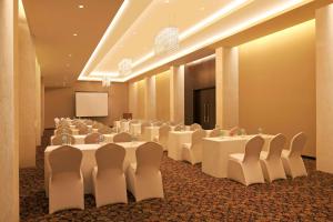 浦那DoubleTree by Hilton-Pune Chinchwad的一间会议室,配有白色的桌椅和屏幕