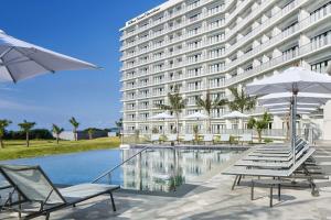 本部Hilton Club The Beach Resort Sesoko的一座建筑前的带椅子和游泳池的酒店
