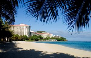 塔穆宁关岛希尔顿spa度假酒店的棕榈树海滩和一些建筑