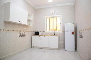 AR RummanahLuxurious Family Apartments 15Mins Drive to Al-Masjid Nabawi - Qaswarah residence的厨房配有白色冰箱和窗户。