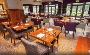 埃文河畔斯特拉特福英国埃文河畔斯特拉特福希尔顿逸林酒店的餐厅设有木桌、椅子和窗户。