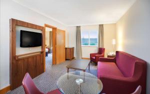 考文垂DoubleTree by Hilton Coventry的酒店客房配有红色椅子和平面电视。