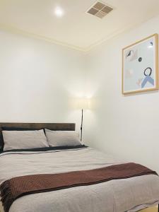 阿德莱德Bundled Bliss 2 bedroom Condo in Adelaide CBD的一张位于白色房间的床,墙上挂着一幅画