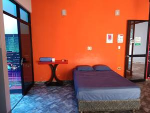 塔拉波托Hospedaje Vegas的一间卧室设有橙色墙壁、一张床和一张桌子