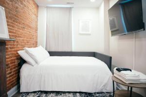 巴尔的摩Sleek and Cozy Micro Fells Point Residence!的卧室配有白色的床和砖墙