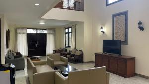 PanyaweuyanGreen Hill Resort Kemuning的客厅配有沙发、电视和椅子