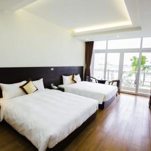 北宁J&C HOTEL的酒店客房设有两张床和大窗户。