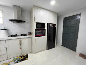 阿罗士打ORKED HOMESTAY的厨房配有白色橱柜和黑色冰箱。