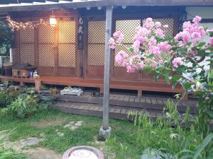 全州市Gugangjae Hanok Stay的院子里的木房子,有粉红色的花