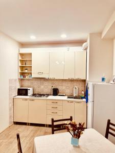 第比利斯Label Apartment的厨房配有白色橱柜、桌子和冰箱。