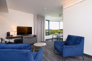 塔尔图Dorpat Hotel的客厅配有蓝色椅子和平面电视