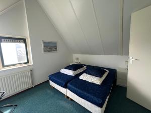 布雷斯肯斯Hello Zeeland - Vakantiehuis Stern 207的一间卧室配有一张带蓝色床单的床和一扇窗户。