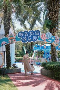 三亚三亚海棠湾喜来登度假酒店（丰富儿童玩乐+S秀表演）的一位在主题公园前行走的孩子的女人