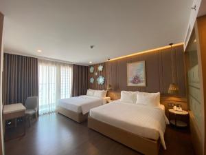 芽庄Virgo Hotel Nha Trang的酒店客房,配有两张床和椅子
