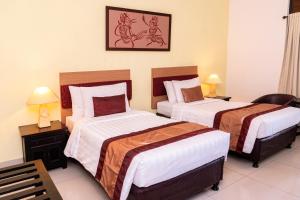 塞米亚克Sarinande Hotel的酒店客房设有两张床,墙上挂着一张照片。