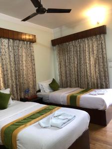 加德满都Bouddha Green Hotel的配有窗帘的酒店客房内的两张床