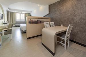 井里汶ASTON Cirebon Hotel and Convention Center的酒店客房带一张床、一张桌子和椅子