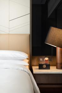西安西安万丽酒店(近大唐不夜城)的一间卧室配有一张床、一盏灯和一台电视