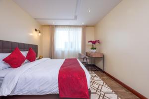 内罗毕Roma Court Serviced Apartments的一间卧室配有一张带红色枕头的大床
