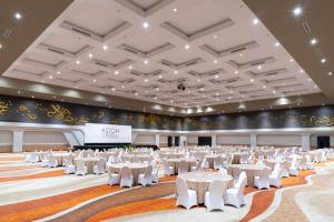 井里汶ASTON Cirebon Hotel and Convention Center的一个带白色桌椅的大型宴会厅