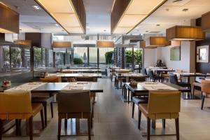 巴塞罗那奥林匹克套房酒店及Spa别墅的餐厅设有桌椅和大窗户。