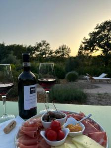 萨杜勒尼亚Casale Terre Rosse Garden的盘肉和一瓶葡萄酒及酒杯