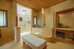 库德岛旺季泳池别墅& Spa的带浴缸、淋浴和长凳的浴室