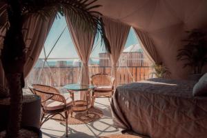 KyzylkumO'MIR glamping эко-отель Актау的配有床、椅子和玻璃桌的房间